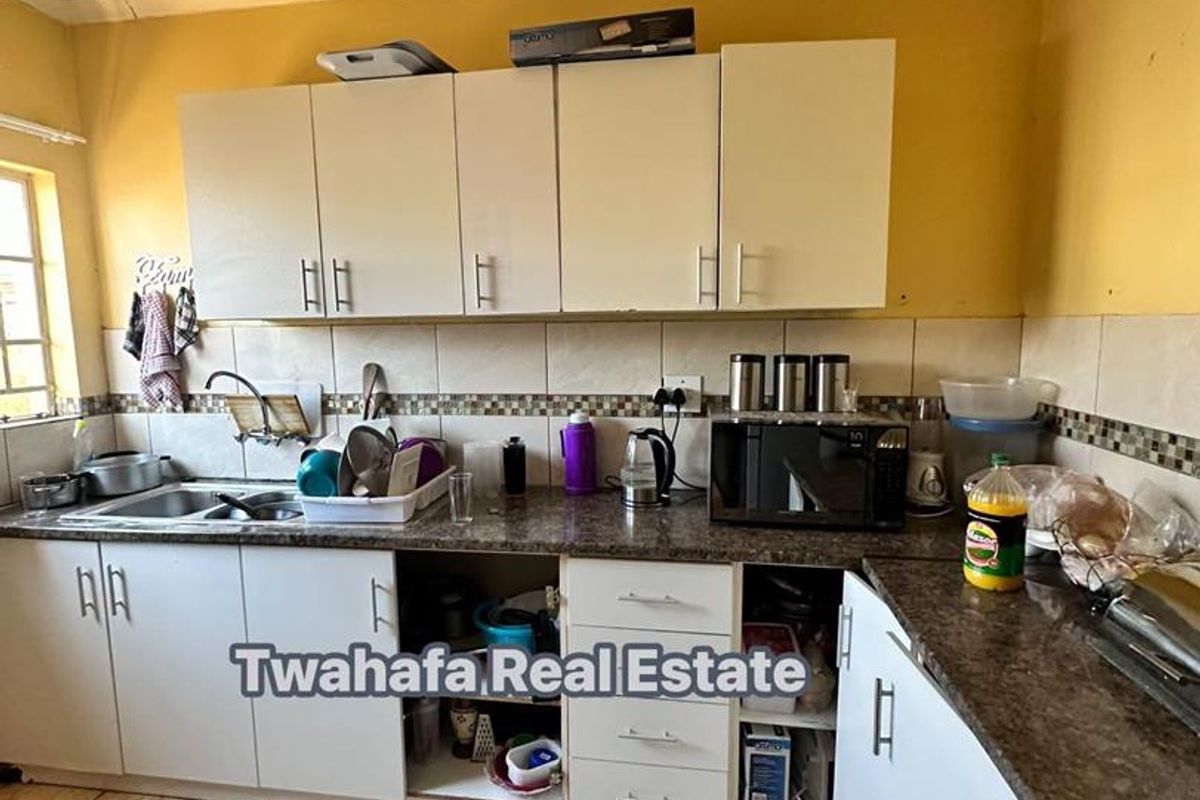 A functional kitchen featuring laminate countertops, tiled backsplash, and built-in cabinetry, currently showing signs of wear and requiring maintenance or cosmetic updates.