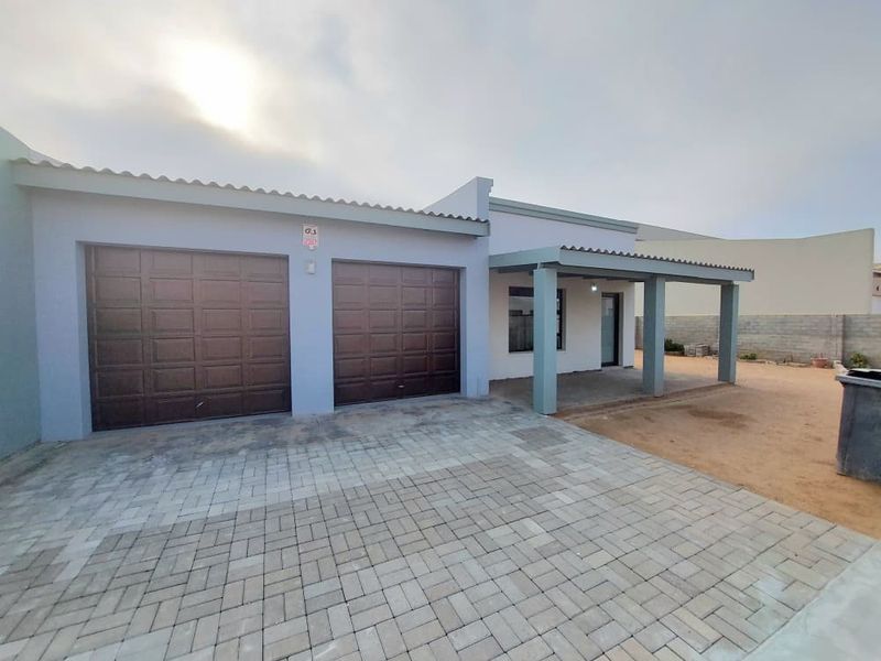 Front exterior view featuring a double garage, paved driveway, and a covered patio area with unfinished landscaping.