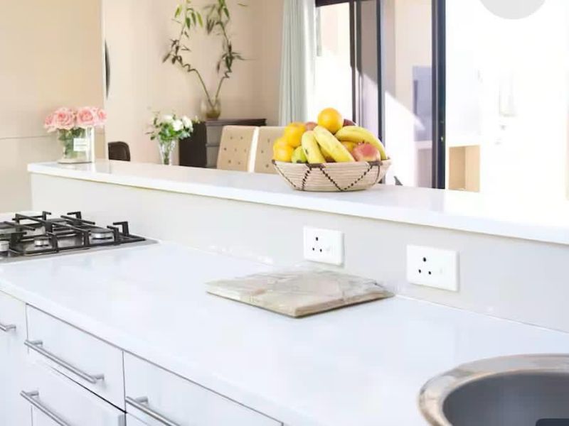 Modern kitchen featuring white cabinetry, stone countertops, a built-in gas hob, and an integrated oven with a stainless steel sink.