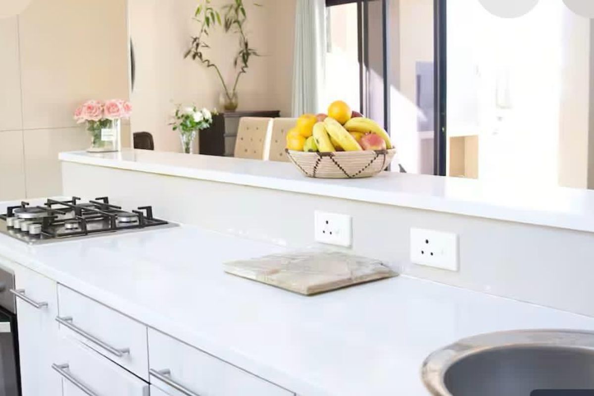Modern kitchen featuring white cabinetry, stone countertops, a built-in gas hob, and an integrated oven with a stainless steel sink.