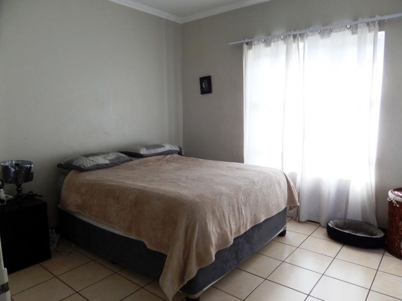 A standard bedroom featuring neutral wall paint and tiled flooring, providing a functional and well-lit space.