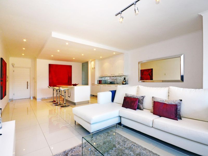 Modern open-plan living area featuring a sleek kitchen with island, tiled flooring, and recessed lighting, creating a bright and cohesive living space.