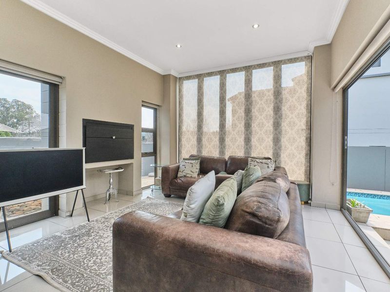 Bright living room featuring tiled floors, recessed lighting, and large sliding glass doors providing direct access to the outdoor pool area.