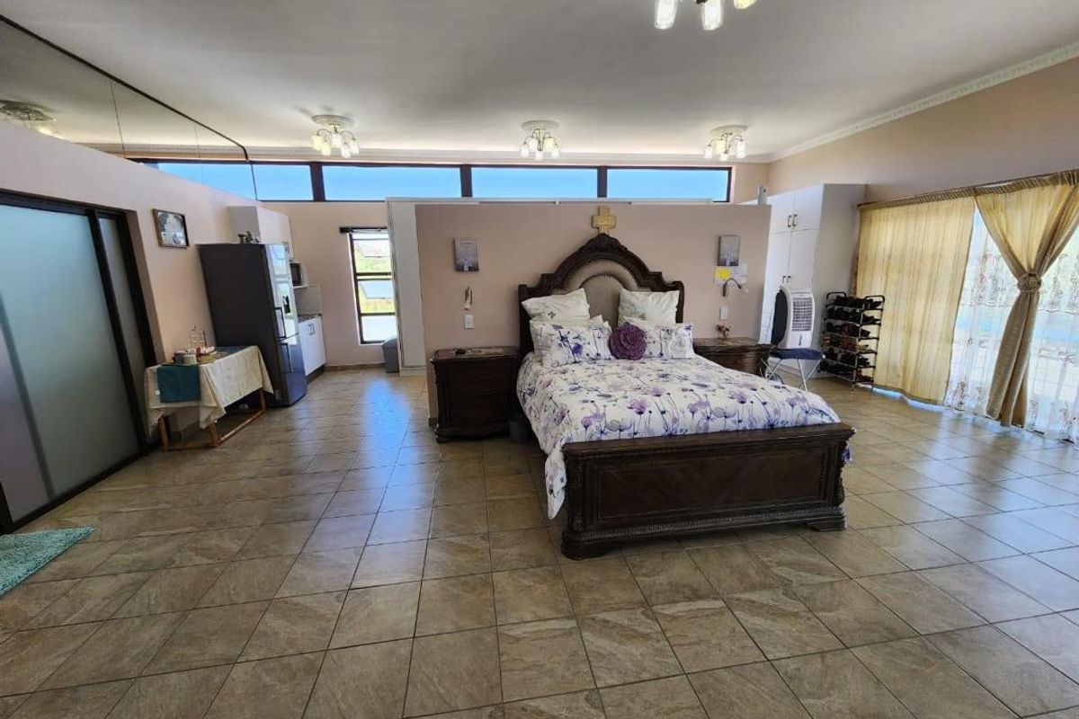 Spacious open-plan bedroom featuring tiled flooring, high-level clerestory windows, and integrated storage, offering a versatile layout with ample natural light.