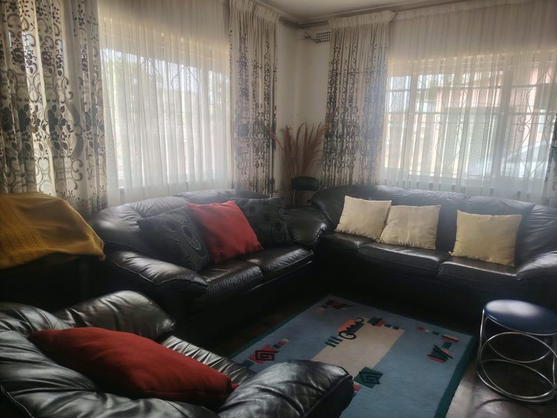A comfortable living room featuring large windows with security bars and curtain rails, offering a bright and functional space.