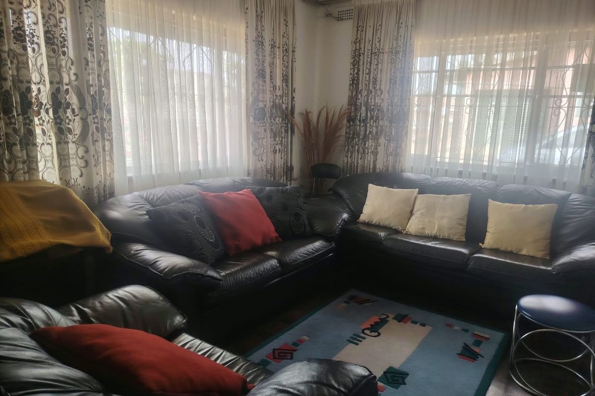 A comfortable living room featuring large windows with security bars and curtain rails, offering a bright and functional space.