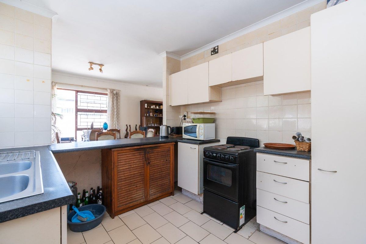A functional kitchen featuring laminate countertops, tiled backsplash, and built-in cabinetry, offering a practical layout with potential for modern updates.
