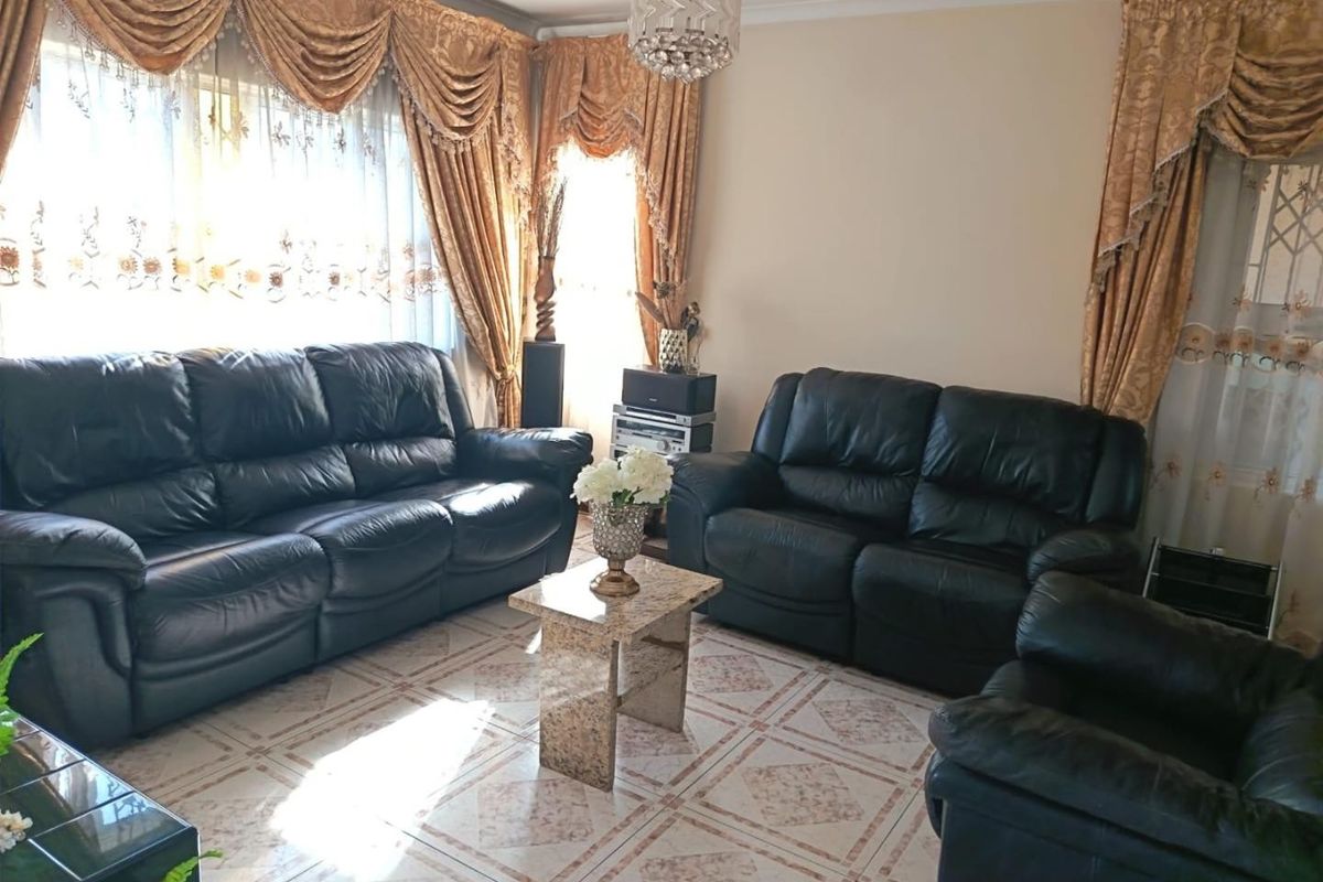 A living room featuring tiled flooring and a decorative crystal chandelier, offering a traditional aesthetic with ample natural light.