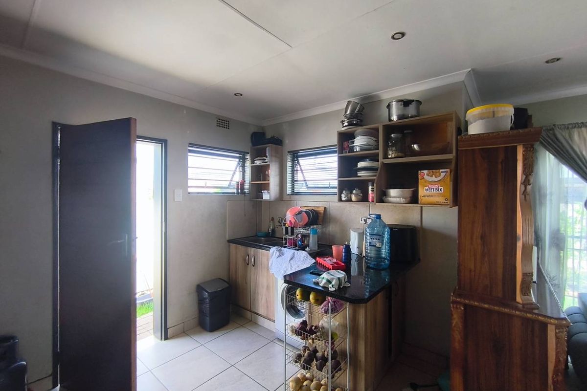 A functional kitchen area featuring built-in cabinetry, dark countertops, tiled flooring, and direct access to the exterior.