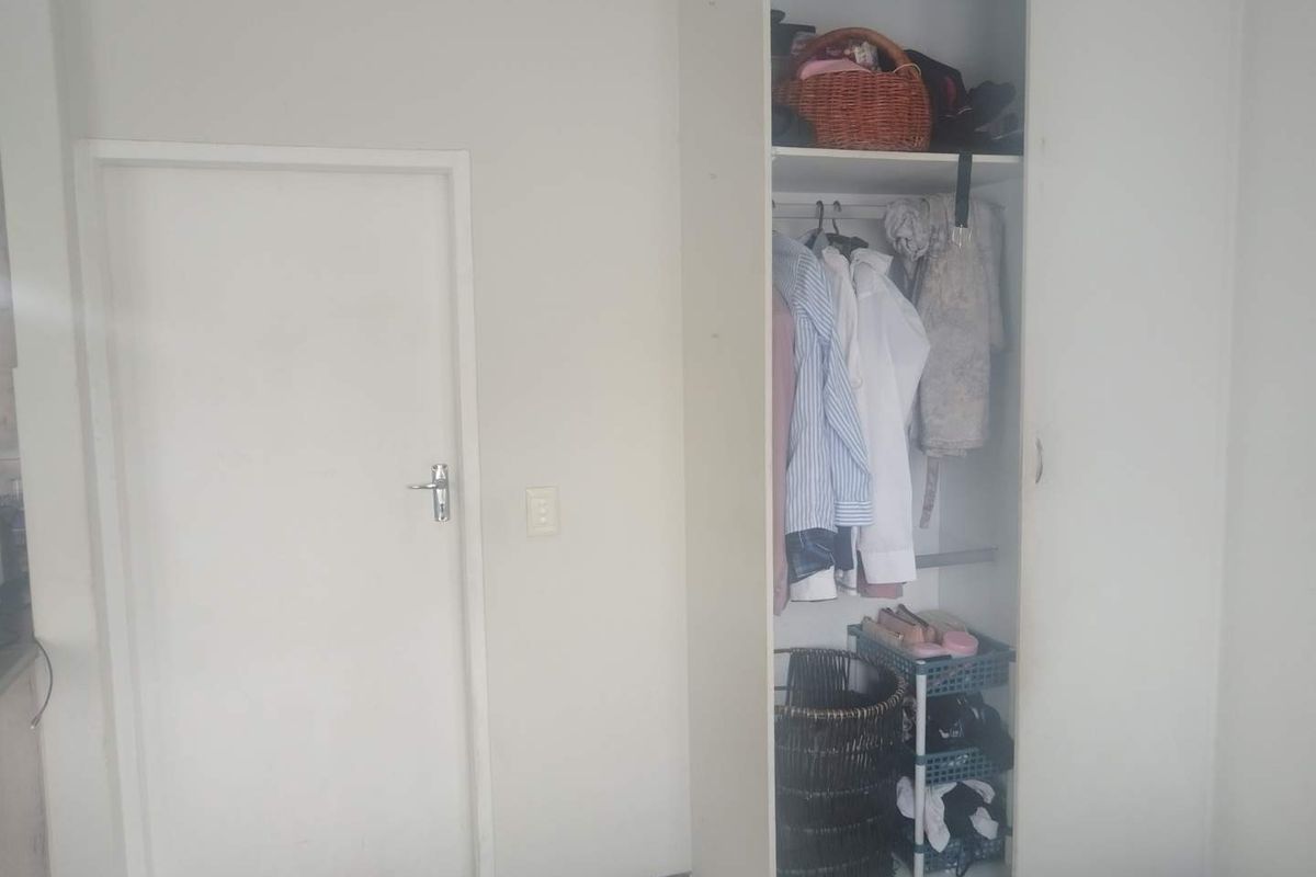 A bedroom interior featuring a built-in wardrobe with shelving and hanging space, alongside a standard interior door.