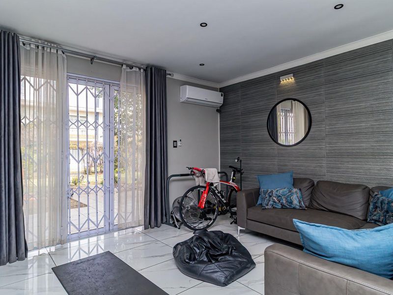 A modern living room featuring large format floor tiles, a textured feature wall, and direct access to the garden through a secure sliding door.