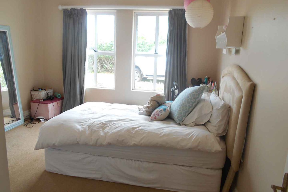 A standard bedroom featuring carpet flooring and double-hung windows, providing natural light and a functional layout.