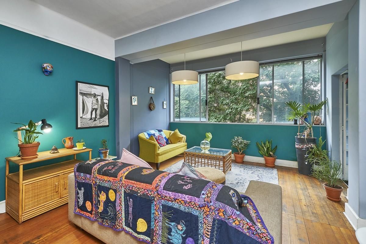 A bright living room featuring polished timber flooring, large windows with garden views, and bold accent walls, creating a warm and inviting atmosphere.