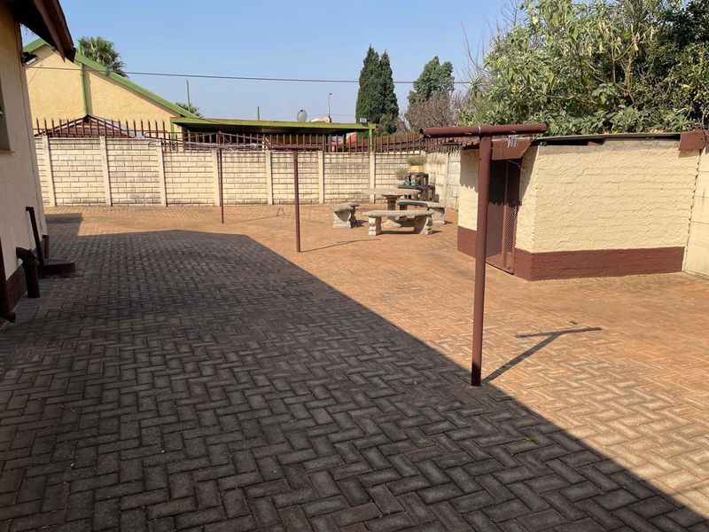A paved rear courtyard featuring a precast concrete boundary wall, a small storage structure, and a metal washing line.