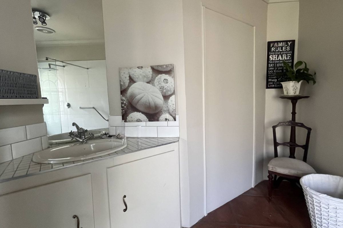 A functional bathroom featuring a vanity with a tiled countertop, inset sink, and a glass-enclosed shower area.