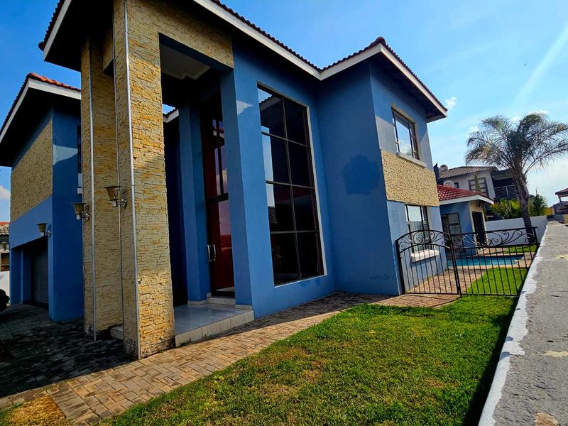 Modern double-story house featuring blue exterior walls with stone cladding accents, large windows, and a paved entrance area.