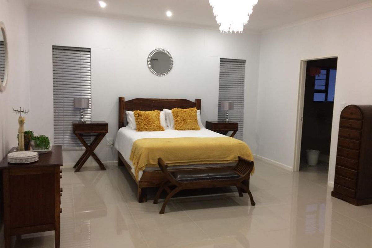 Spacious bedroom featuring tiled flooring, recessed downlighting, a decorative chandelier, and dual windows fitted with modern venetian blinds.