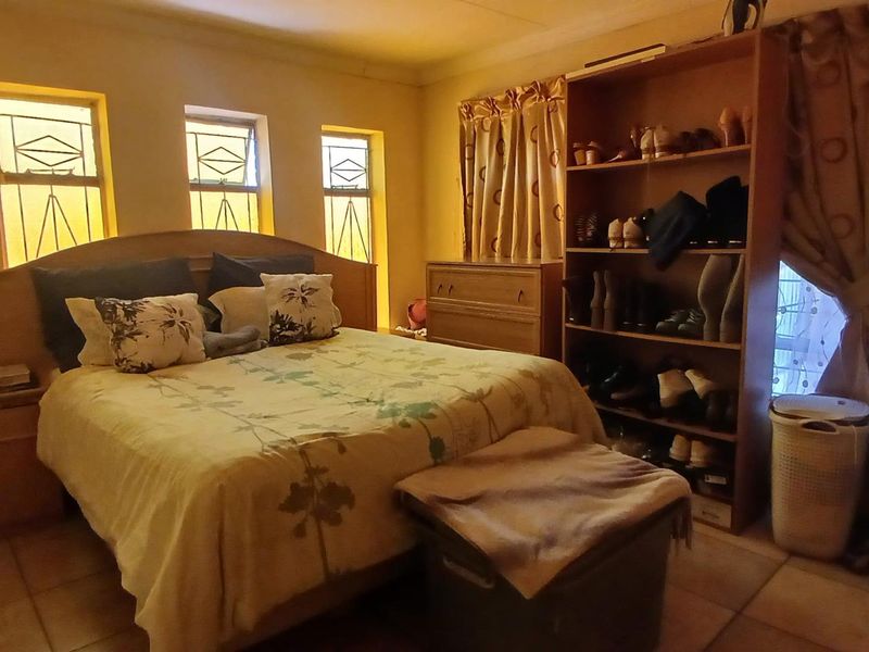 A bedroom featuring tiled flooring and three vertical windows, providing natural light and a functional layout.