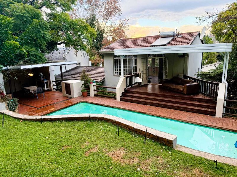 Outdoor entertainment area featuring a swimming pool, timber decking, and a covered patio with direct access to the main dwelling.