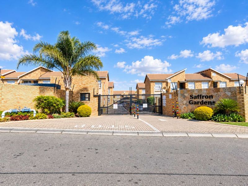Front entrance view of Saffron Gardens apartment complex featuring brick facades, paved driveway, and secure gated access.