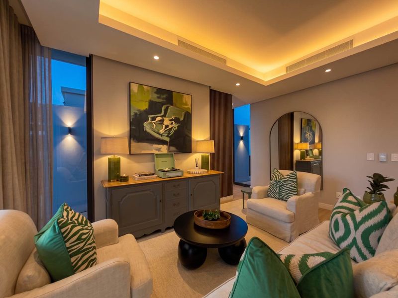 A modern, well-lit living room featuring a recessed ceiling with cove lighting, ducted air conditioning, and elegant timber wall paneling.