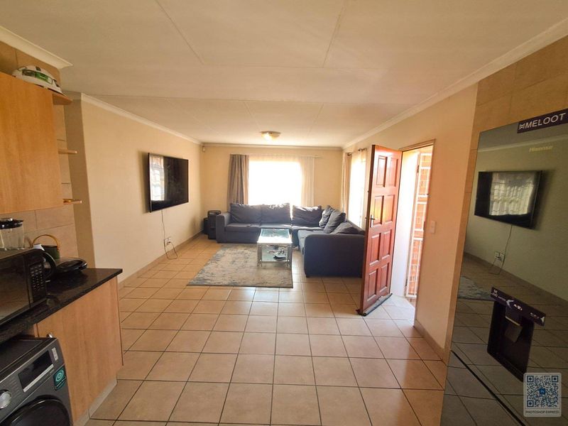Open-plan living area featuring tiled flooring, integrated kitchen cabinetry with granite countertops, and direct access to the exterior.