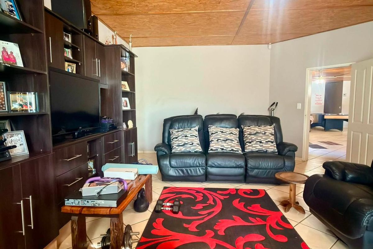A living room featuring built-in dark wood cabinetry, tiled flooring, and a wood-paneled ceiling with an integrated fan.