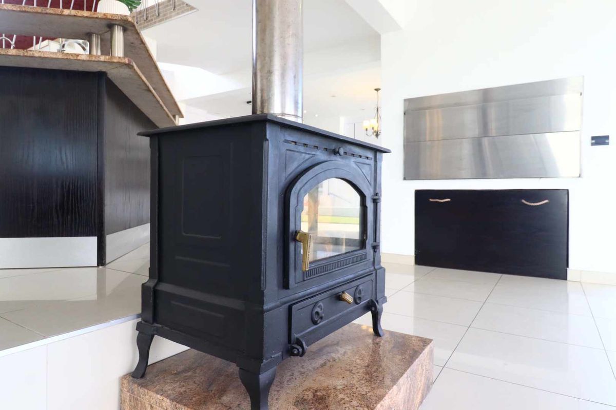 A modern living space featuring a prominent black cast-iron fireplace set on a raised stone hearth with polished tile flooring.