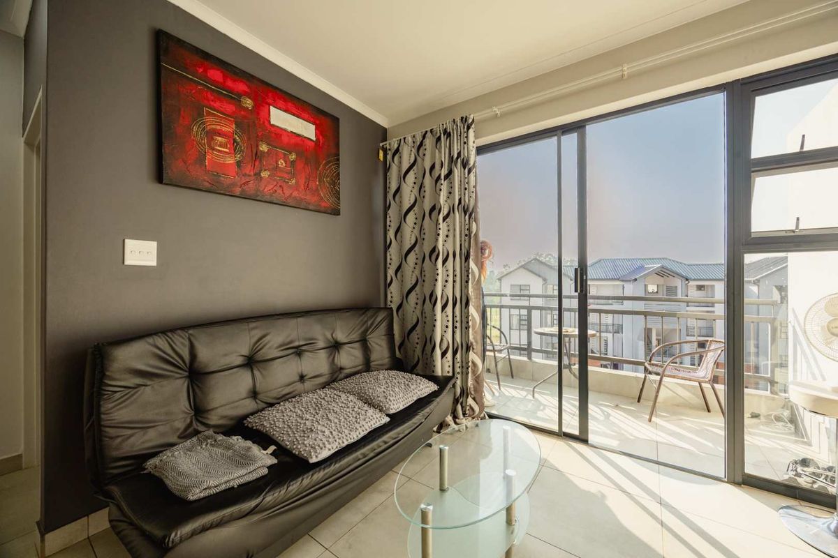 A bright living room featuring tiled flooring and large sliding glass doors that provide direct access to a private balcony.