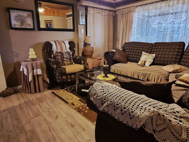 A cozy living room featuring laminate flooring and a panelled ceiling, offering a comfortable and traditional living space.