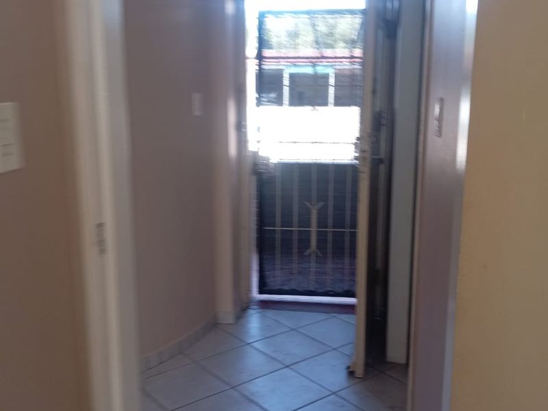 A functional hallway featuring tiled flooring and a security gate leading to the exterior, providing a clean transition space within the apartment.