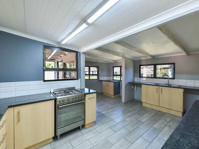 Spacious kitchen featuring light wood cabinetry, dark granite countertops, a gas stove, and tiled flooring with an open-plan layout.