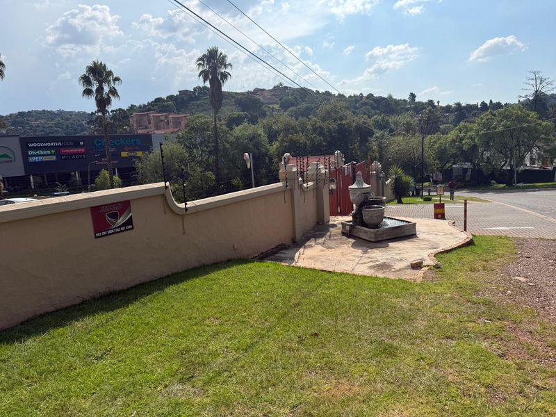 Front exterior view of the property featuring a perimeter wall with electric fencing, a decorative water fountain, and paved driveway access.