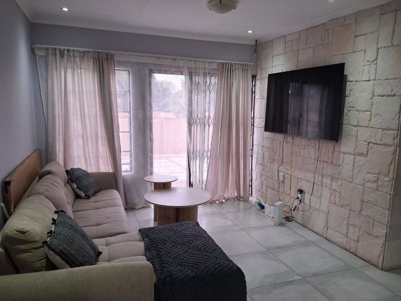 Living room featuring a textured stone accent wall, tiled flooring, and sliding glass doors providing access to the outdoor area.