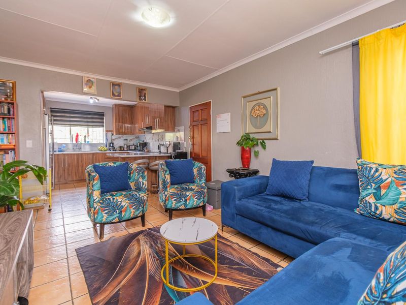 Open plan living area featuring tiled flooring and a functional kitchen with built-in cabinetry and a breakfast bar.