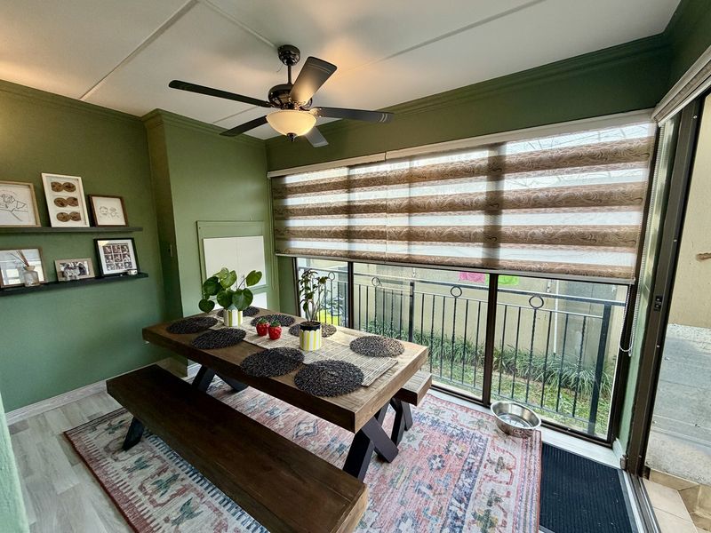 A dining area featuring a ceiling fan, floating wall shelves, and large sliding glass doors leading to an outdoor space with a metal balustrade.