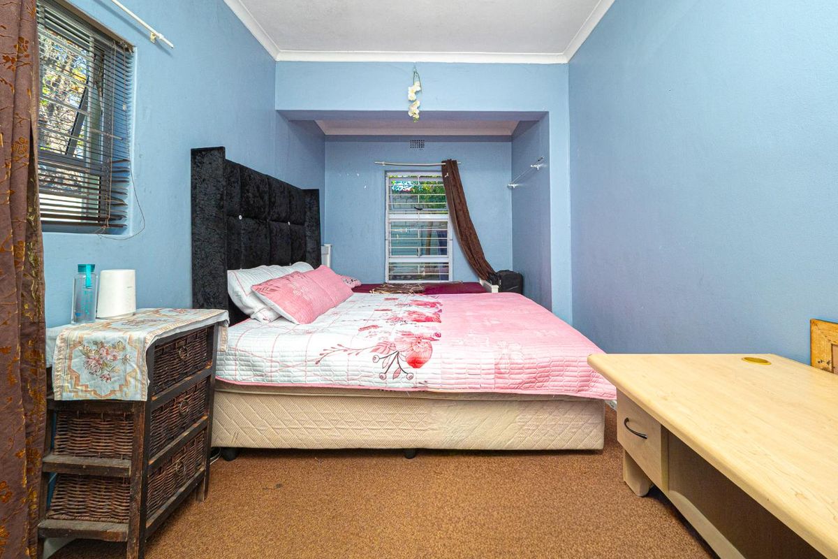 A bedroom featuring blue walls, carpet flooring, and dual windows with aluminium frames.