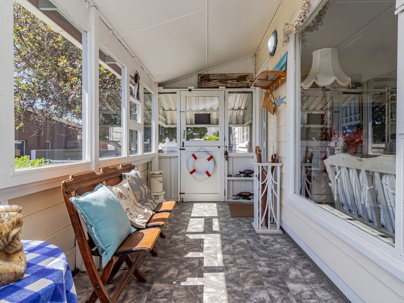 A bright, enclosed sunroom or patio featuring large windows, tiled flooring, and a screen door, offering a versatile space for relaxation.