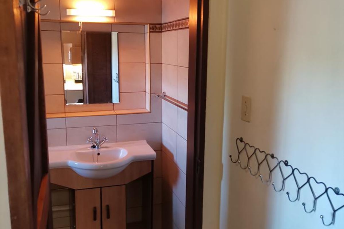 A functional bathroom featuring a vanity cabinet with integrated basin, wall-mounted mirror, and tiled splashback.