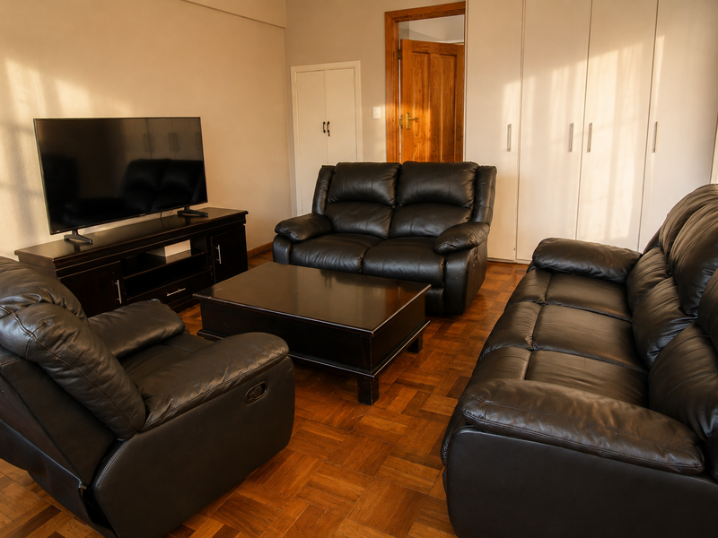 A living room featuring classic parquet flooring and extensive built-in storage cupboards, providing a functional and traditional living space.