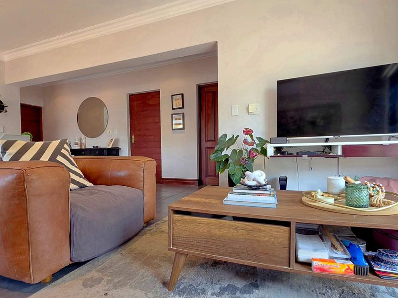 A comfortable living room featuring tiled flooring, decorative coving, and a wall-mounted media shelf, providing a functional and inviting space.