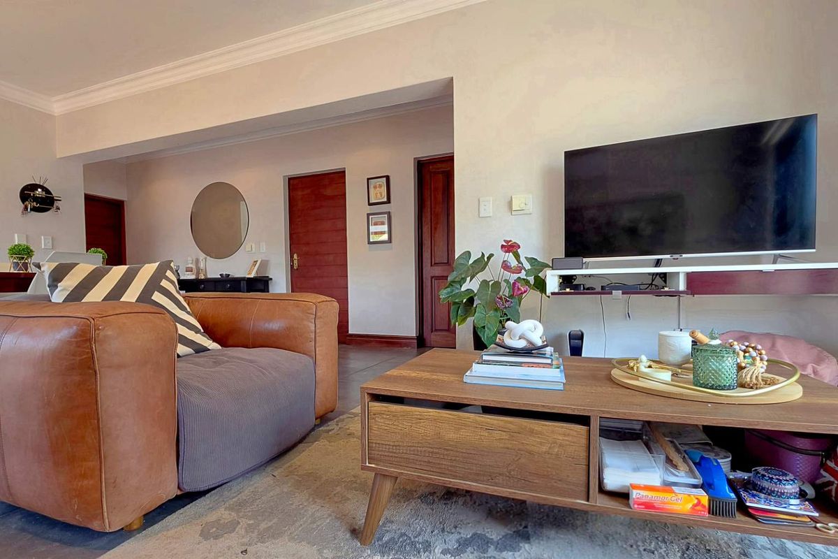 A comfortable living room featuring tiled flooring, decorative coving, and a wall-mounted media shelf, providing a functional and inviting space.