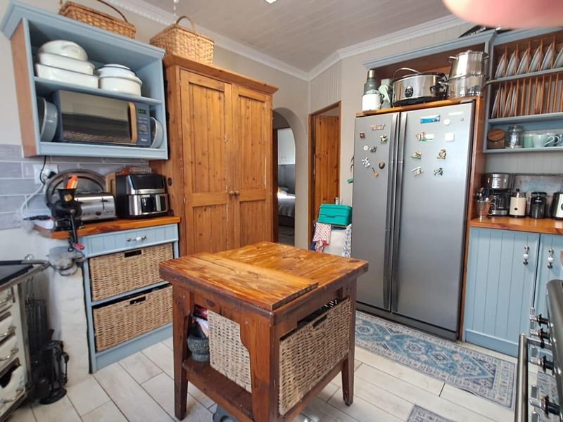 A rustic-style kitchen featuring blue cabinetry, wooden countertops, subway tile backsplash, and a central wooden island, offering a warm and functional cooking space.