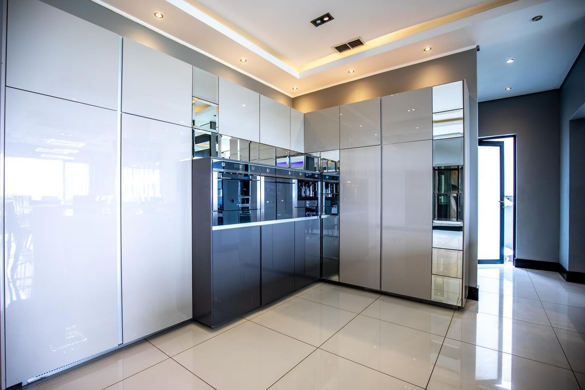 Modern kitchen featuring high-gloss cabinetry, integrated ovens, recessed ceiling lighting, and polished floor tiles.