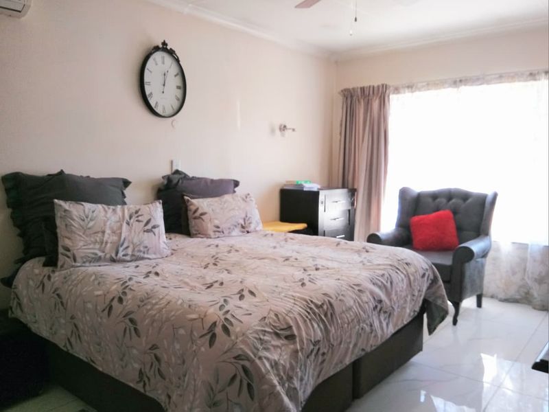 A bedroom featuring tiled flooring, a ceiling fan, and an air conditioning unit, providing a functional and comfortable living space.