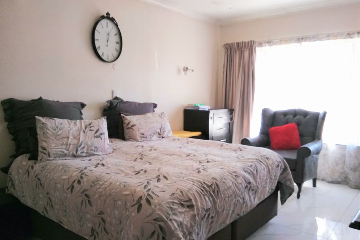 A bedroom featuring tiled flooring, a ceiling fan, and an air conditioning unit, providing a functional and comfortable living space.