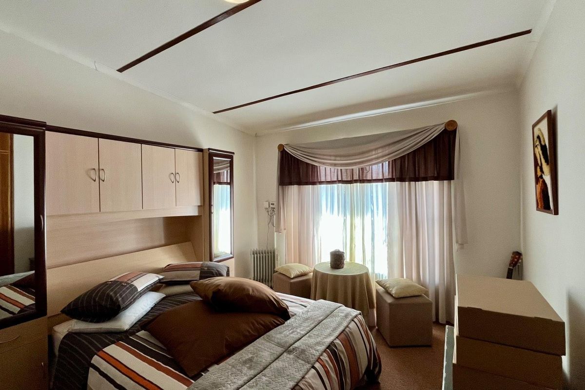 A bedroom featuring built-in cabinetry, integrated wardrobe units, and a radiator, offering a functional layout with natural light.