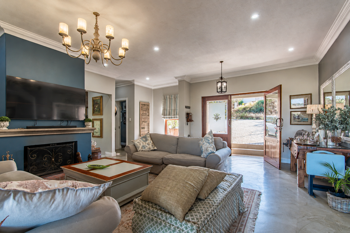 Spacious living room featuring a fireplace with a blue feature wall, polished concrete floors, crown molding, and direct access to the exterior.