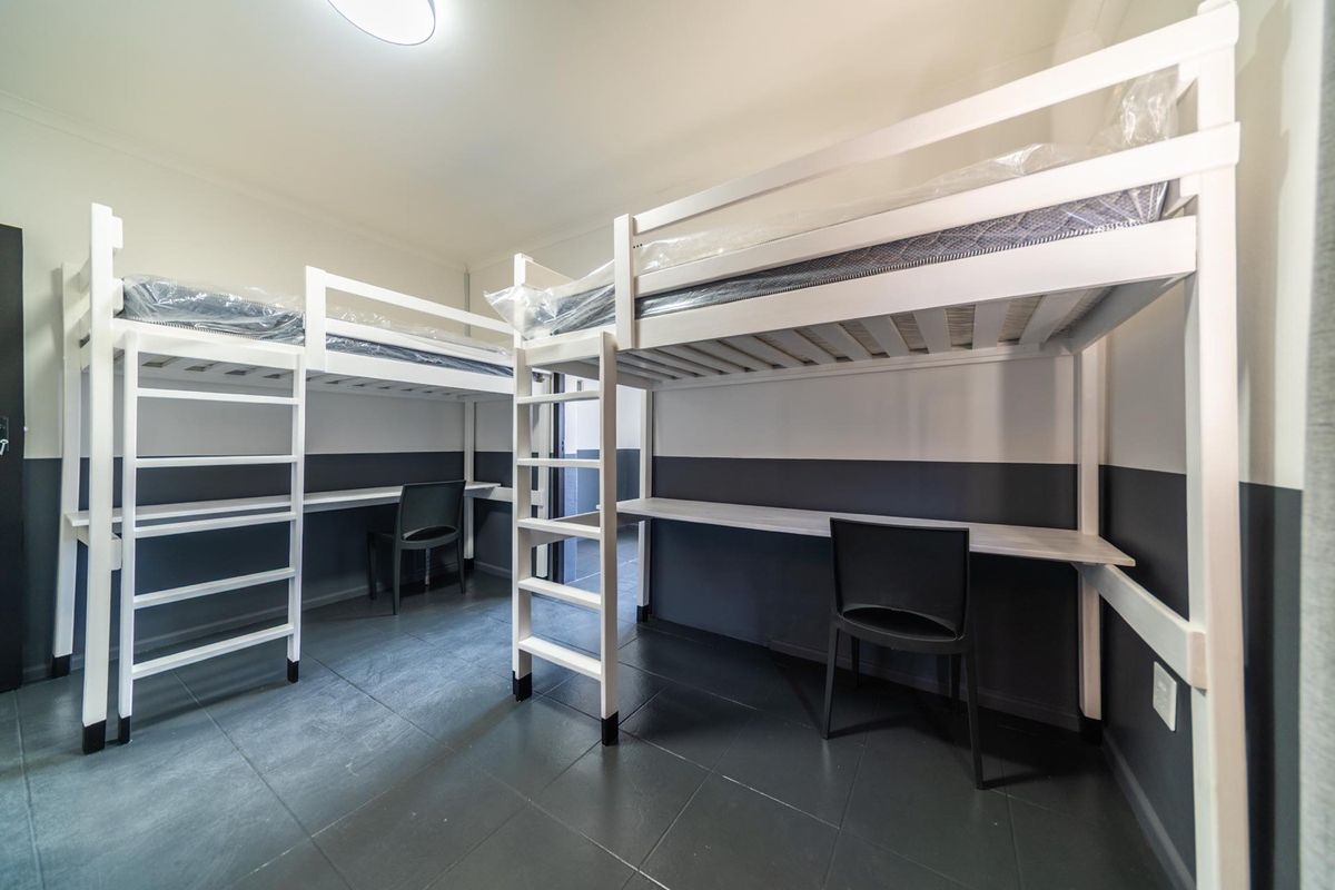 A functional bedroom featuring built-in desks and tiled flooring, designed for efficient use of space.