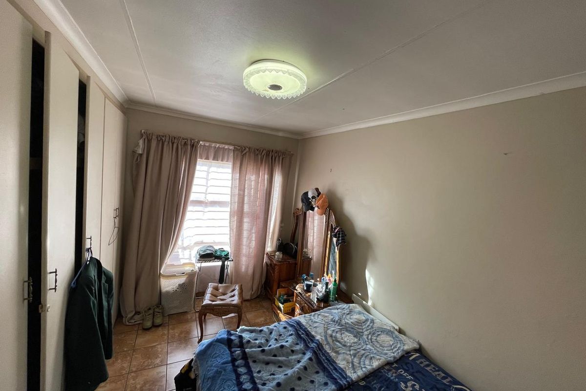 A bedroom featuring built-in cupboards, tiled flooring, and a central ceiling light fixture.